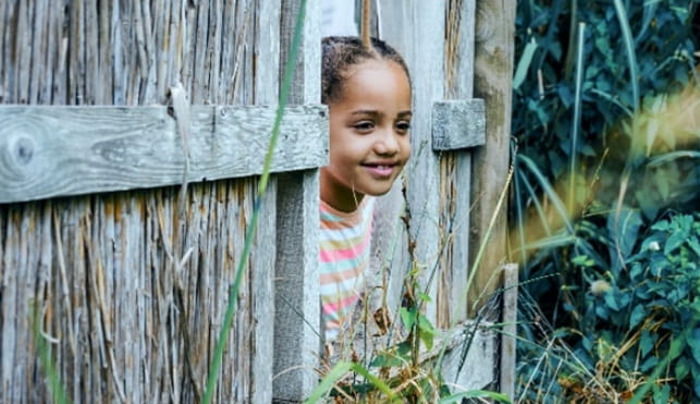 Child peeking through a fence